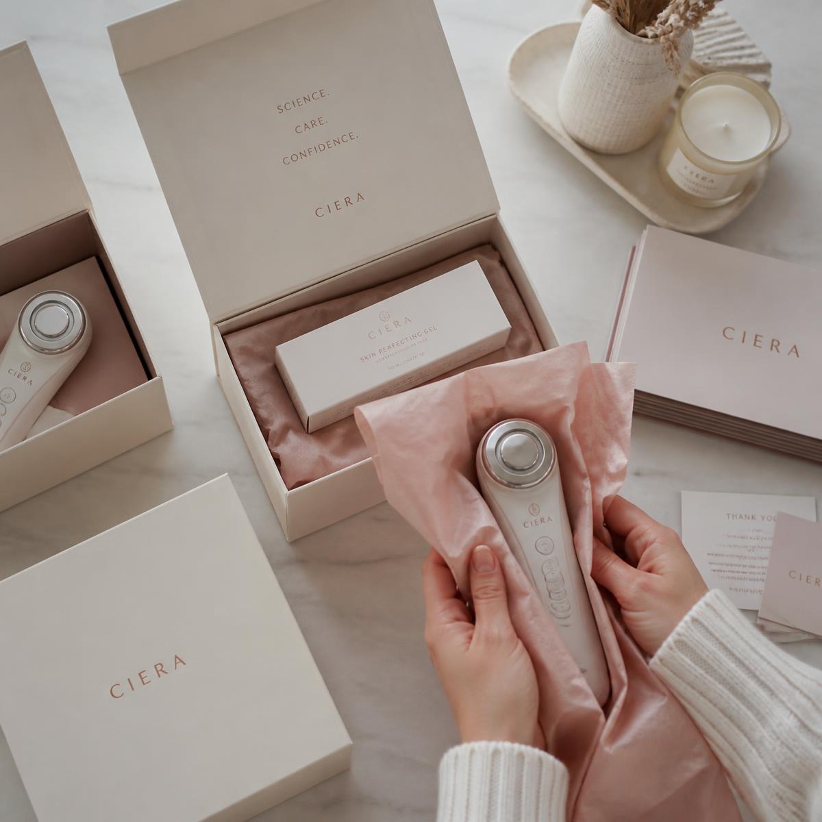 Productos de beauty tech siendo preparados en cajas crema con papel rosado
